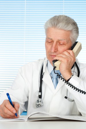 Doctor on phone writing into notebook