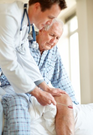 Doctor checking elderly man's knee reflex